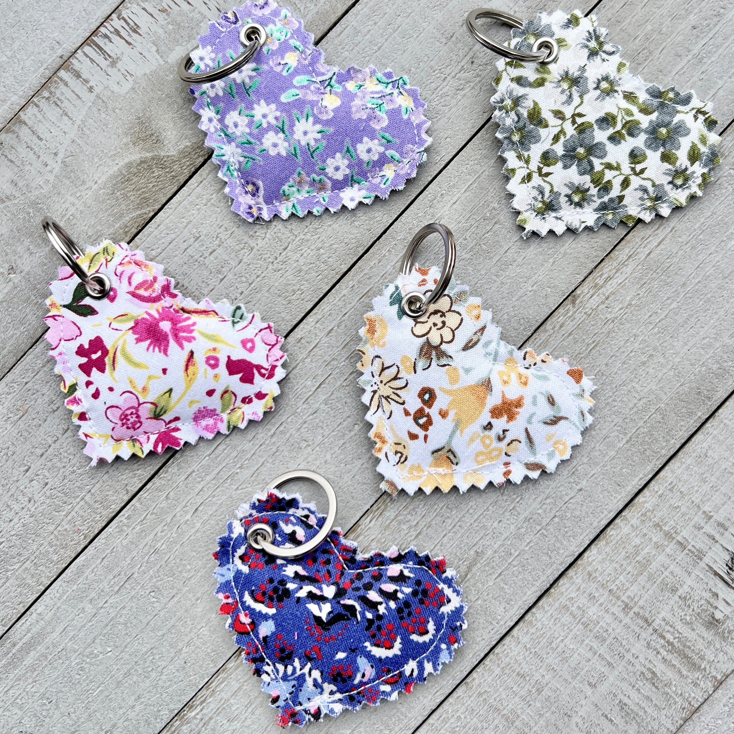 Five floral-patterned keychains on a wooden surface