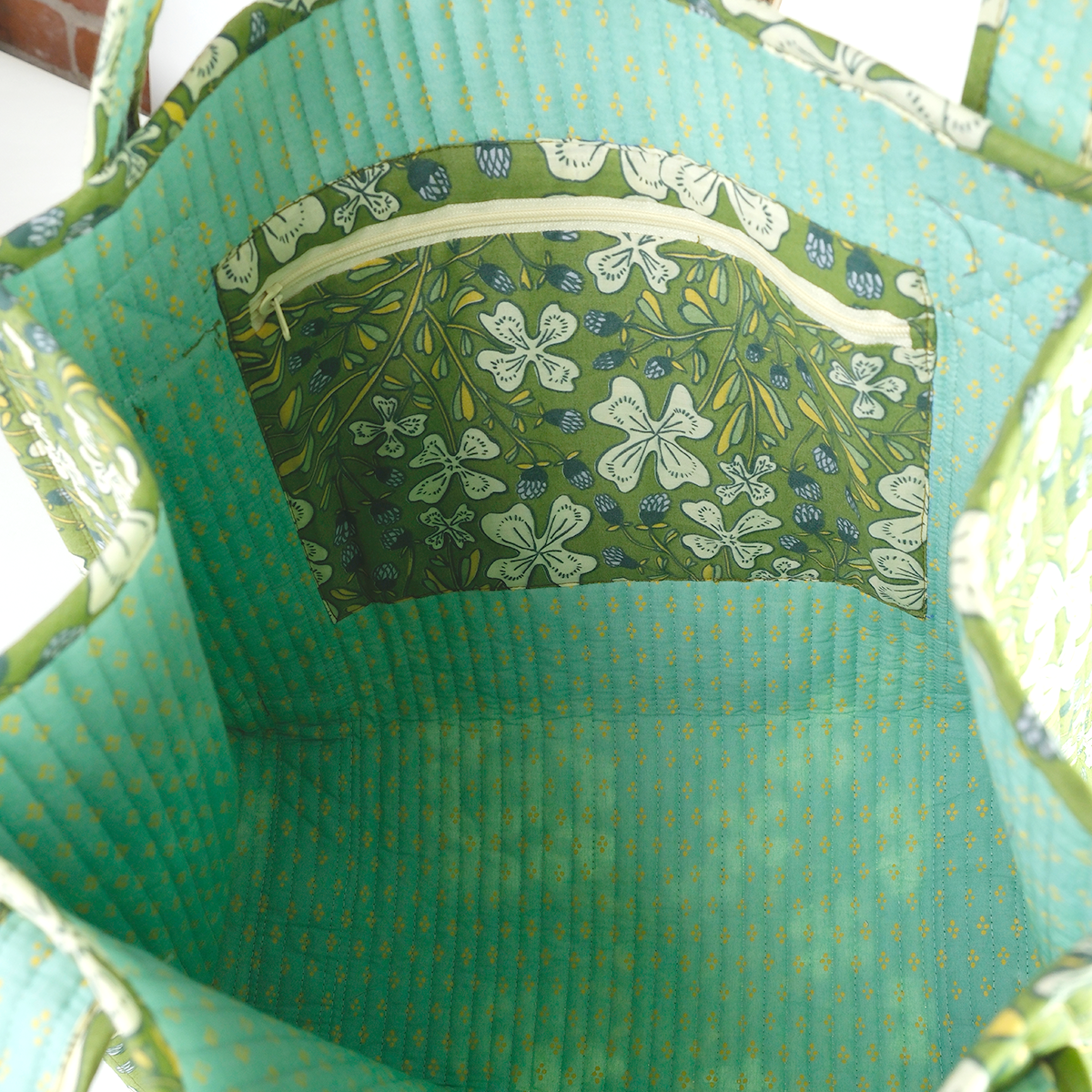 Close-up of a green fabric bag with floral patterned pocket.