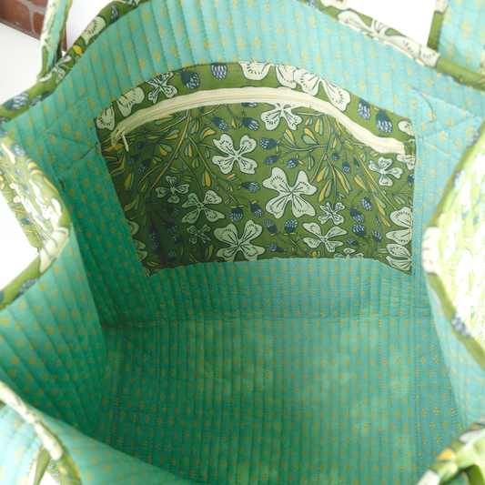 Close-up of a green fabric bag with floral patterned pocket.