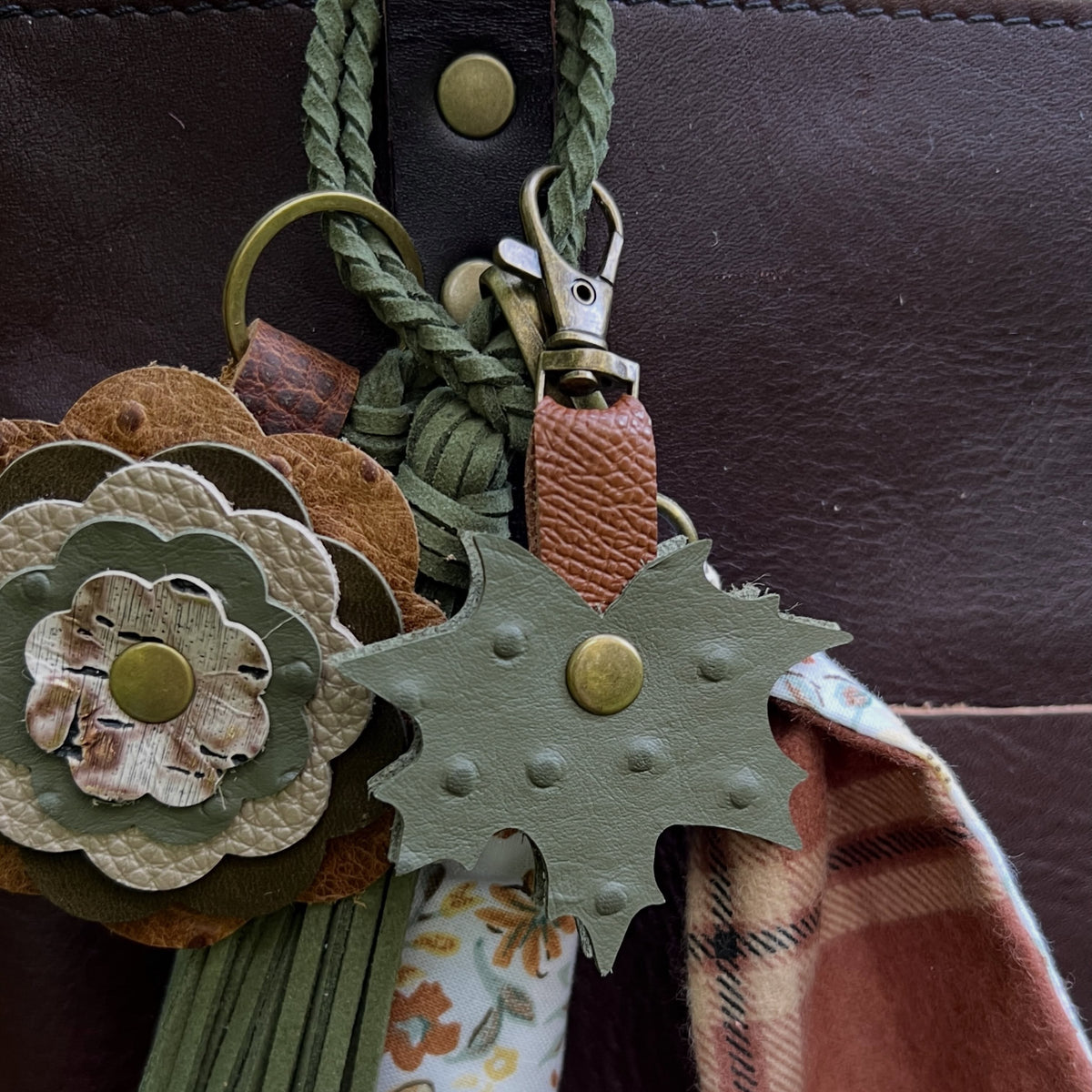 bag charms layered on braided tassel on brown tote