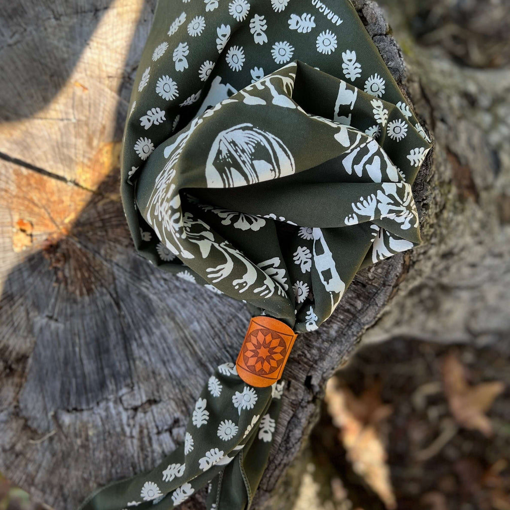 leather bandana slide on Folded green fabric with white patterns on a wooden surface