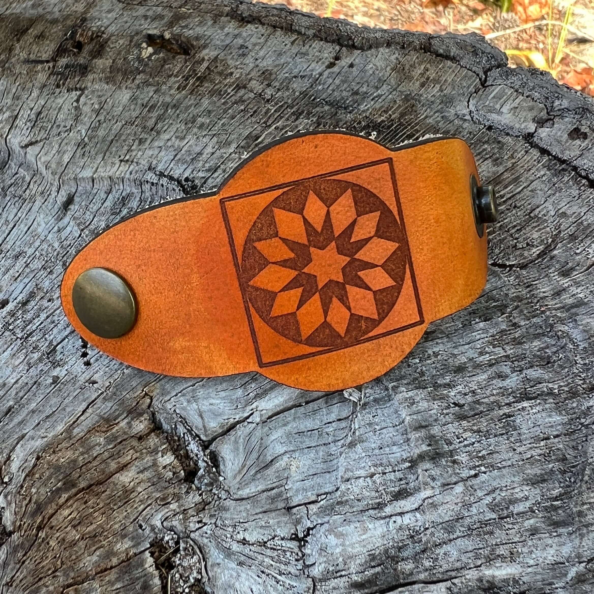 Brown leather bandana slide with star design on a wooden surface