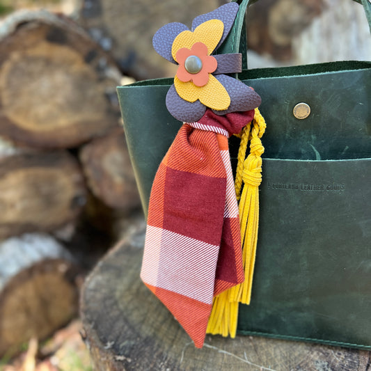 leather butterfly snap on bag charm in burgundy, yellow and orange shown with plaid scarf and yellow tassel