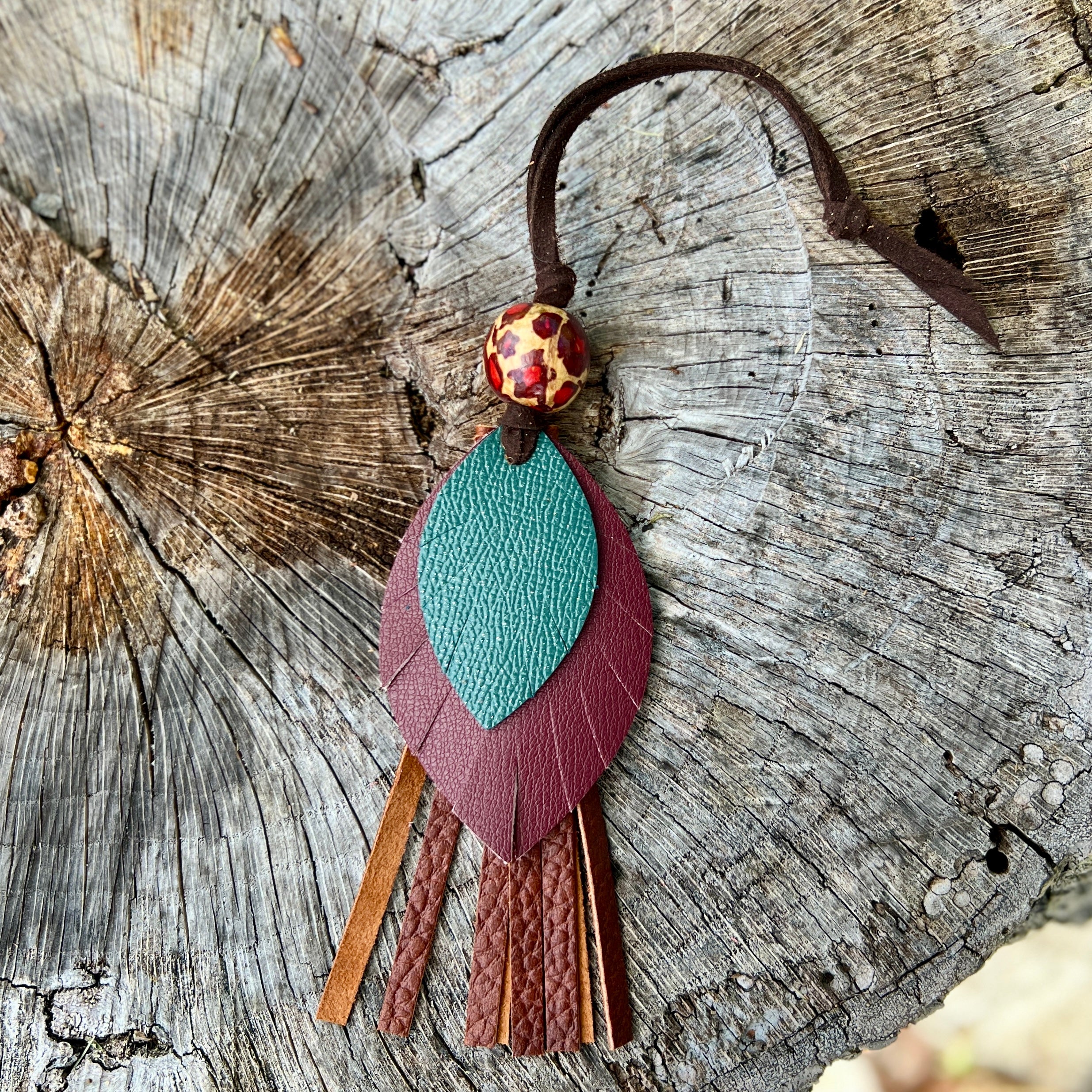 Decorative keychain with leaf design on a wooden surface