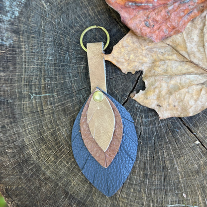 leather flower bag charm in brown and blue on wooden surface