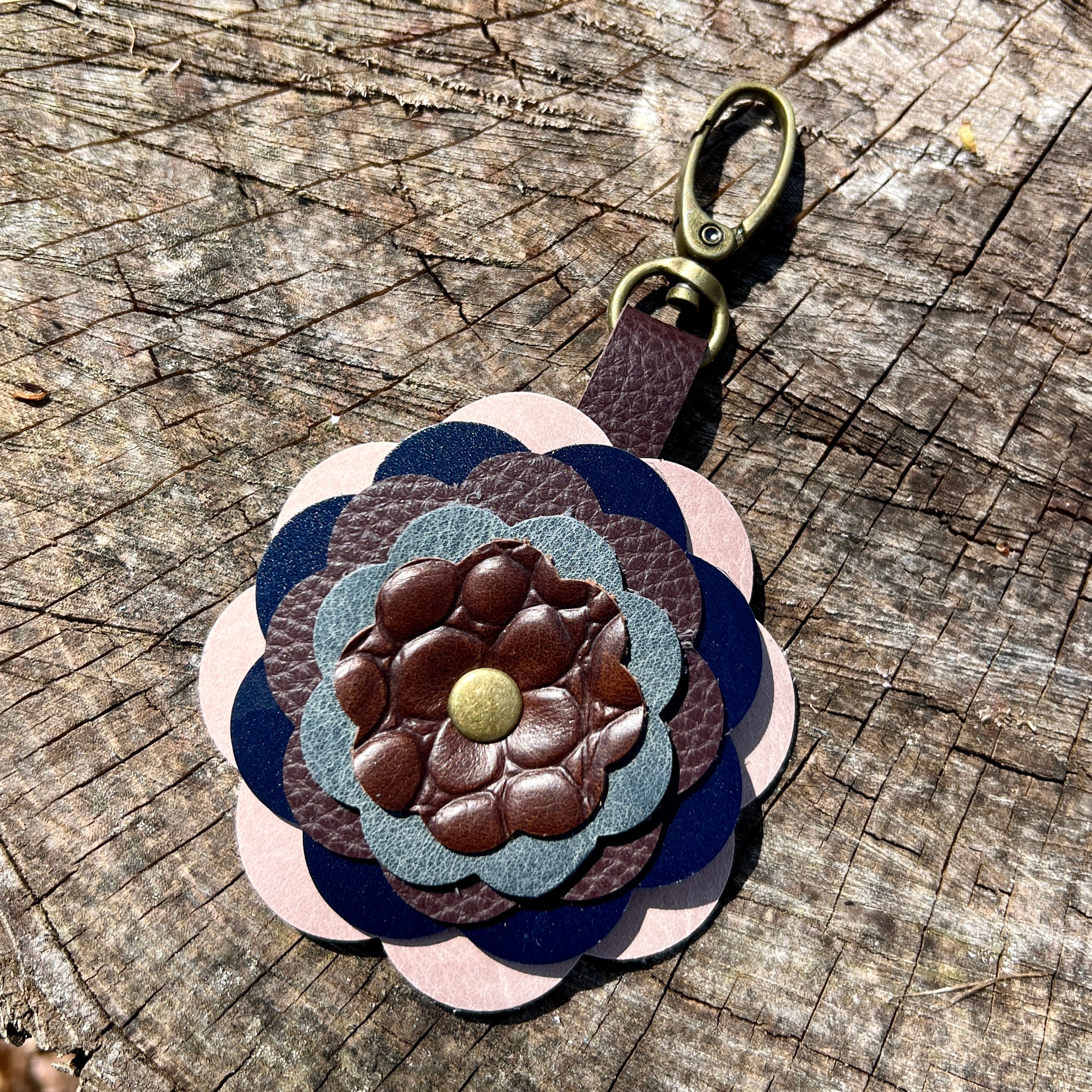 leather flower key chain in blue and brown  on a wooden surface