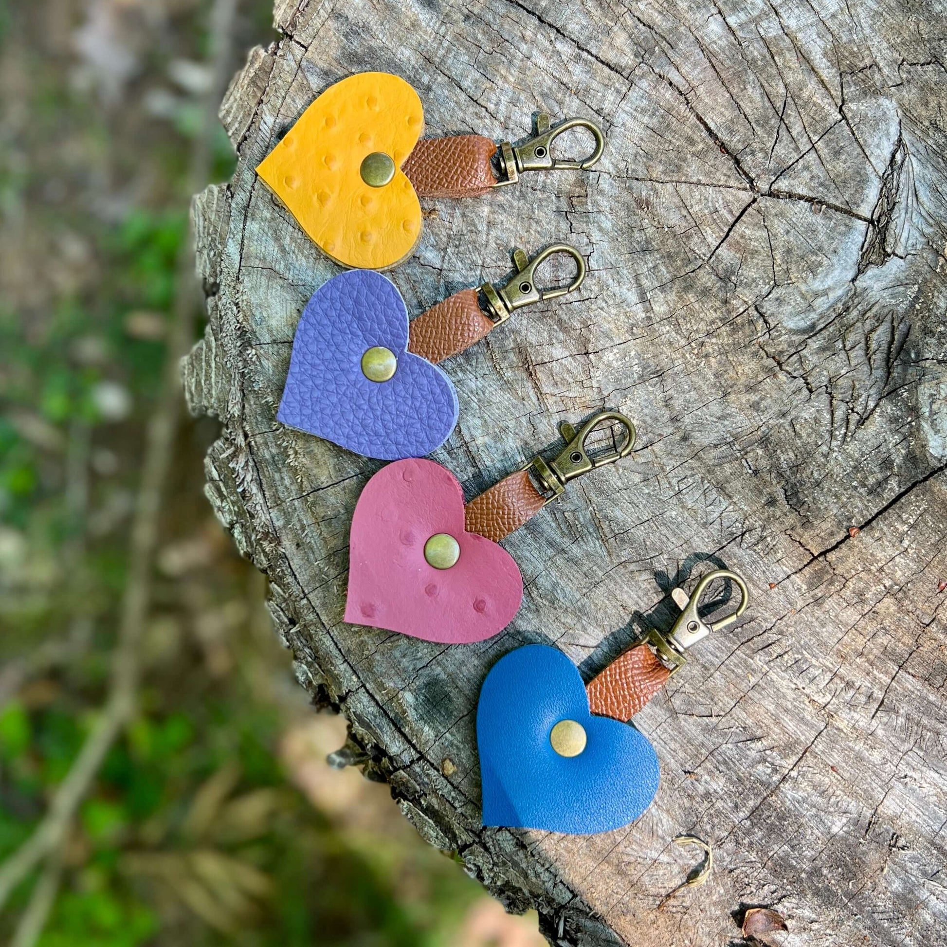 Colorful mini leather heart bag charms on a wooden surface