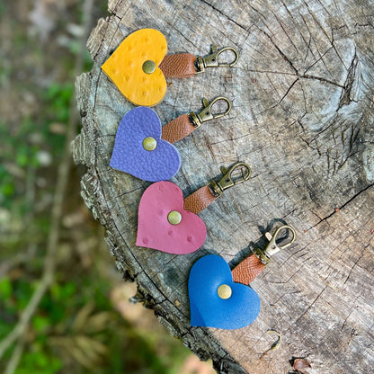Colorful mini leather heart bag charms on a wooden surface