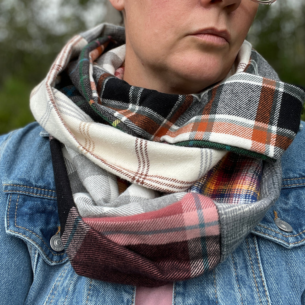 Person wearing a plaid scarf with a denim jacket outdoors