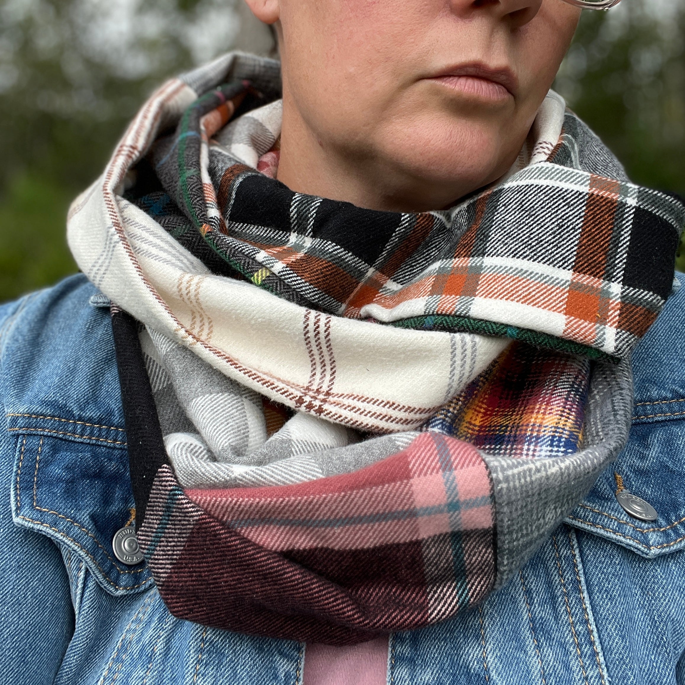 Person wearing a plaid scarf with a denim jacket outdoors