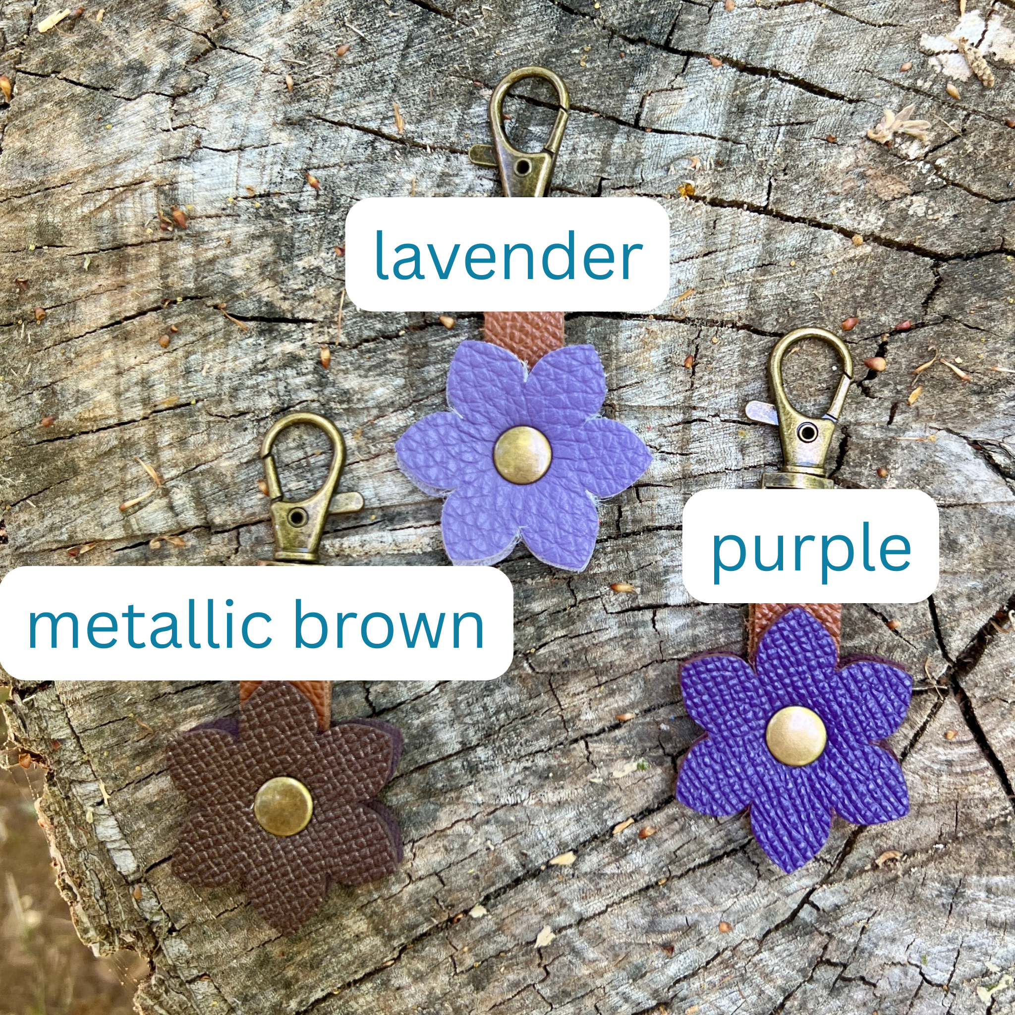 Flower-shaped keychains in lavender, purple, and metallic brown on a wooden surface.