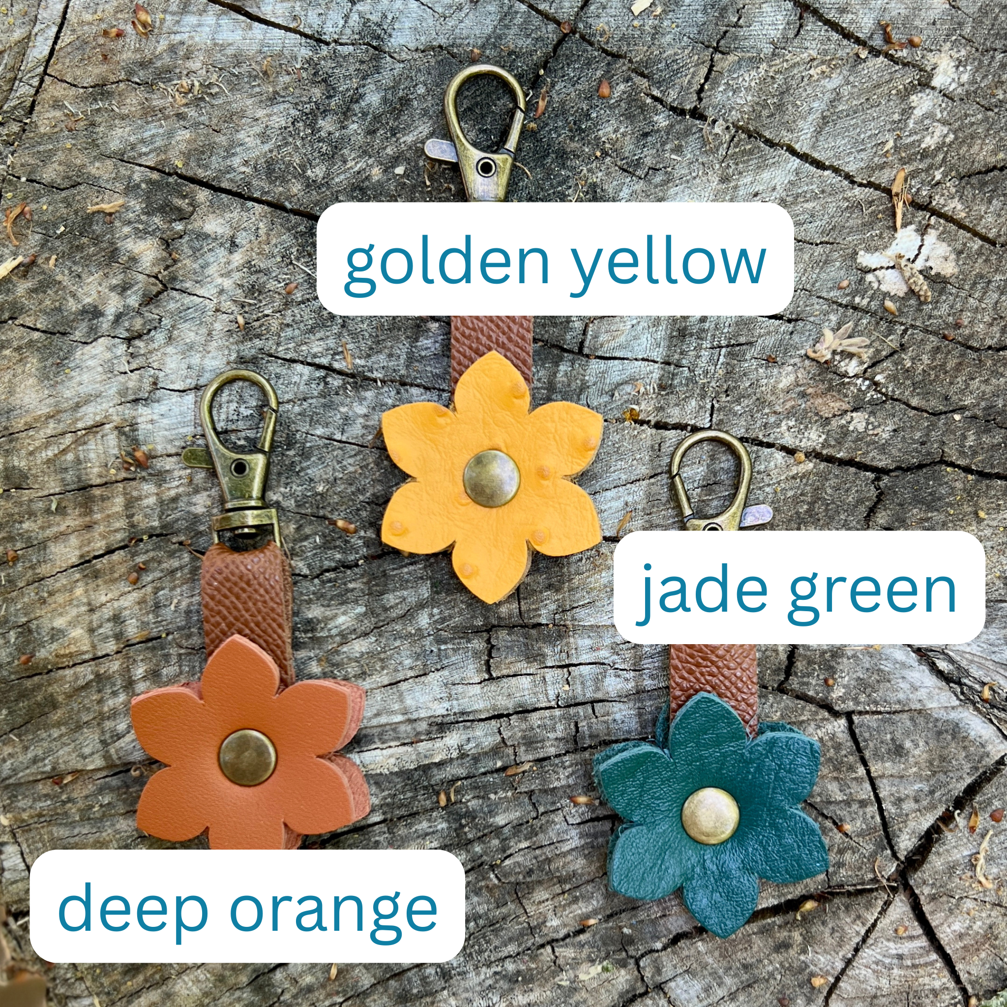 Three flower-shaped keychains in different colors on a wooden surface.