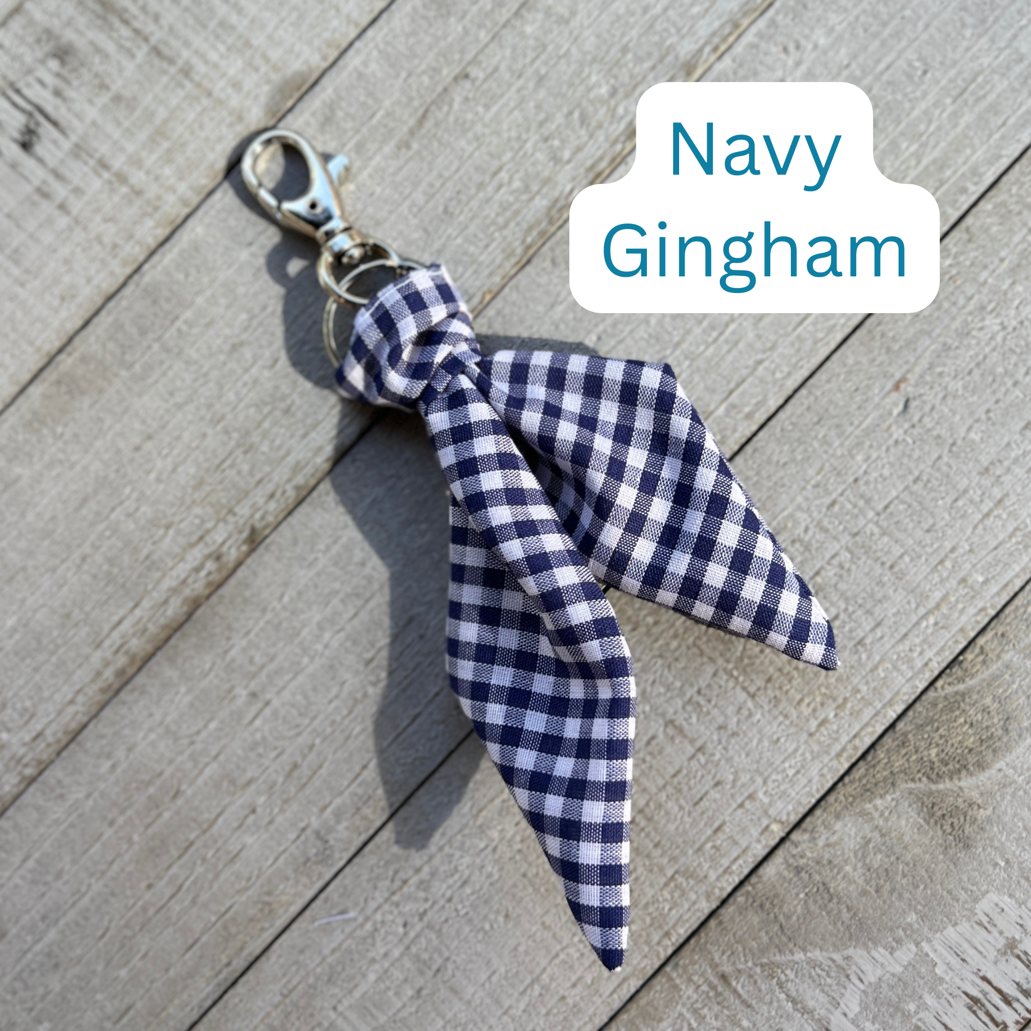 Navy gingham key chain with a bow on a wooden surface