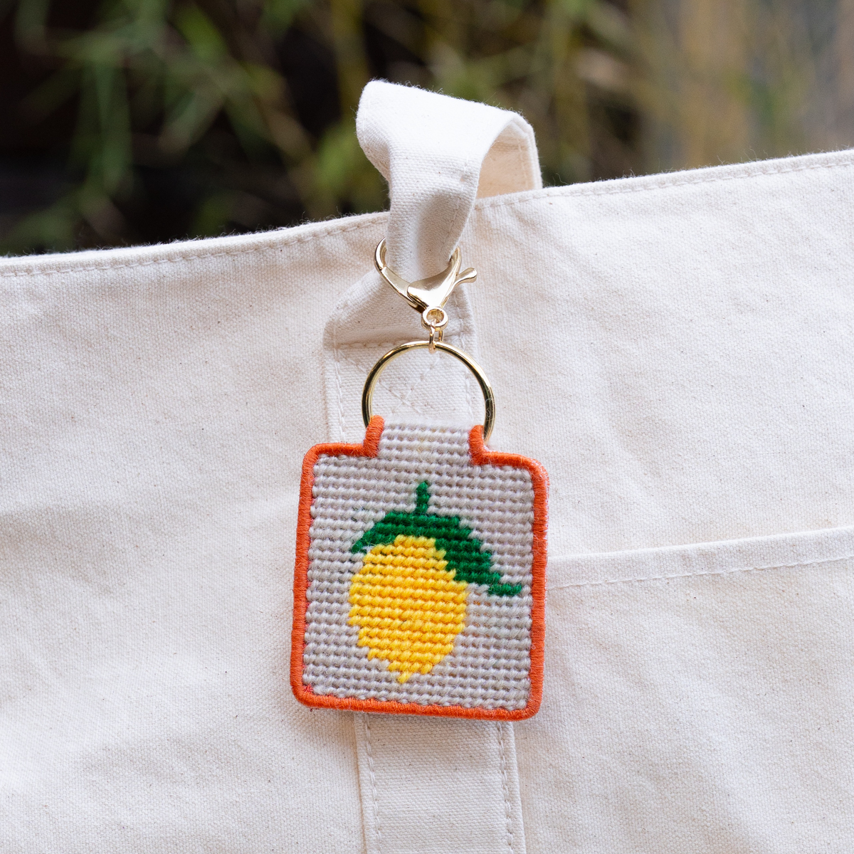 needlepoint keychain kit with yellow lemon on white tote
