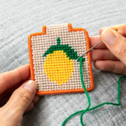 needlepoint keychain kit with yellow lemon with hands sewing