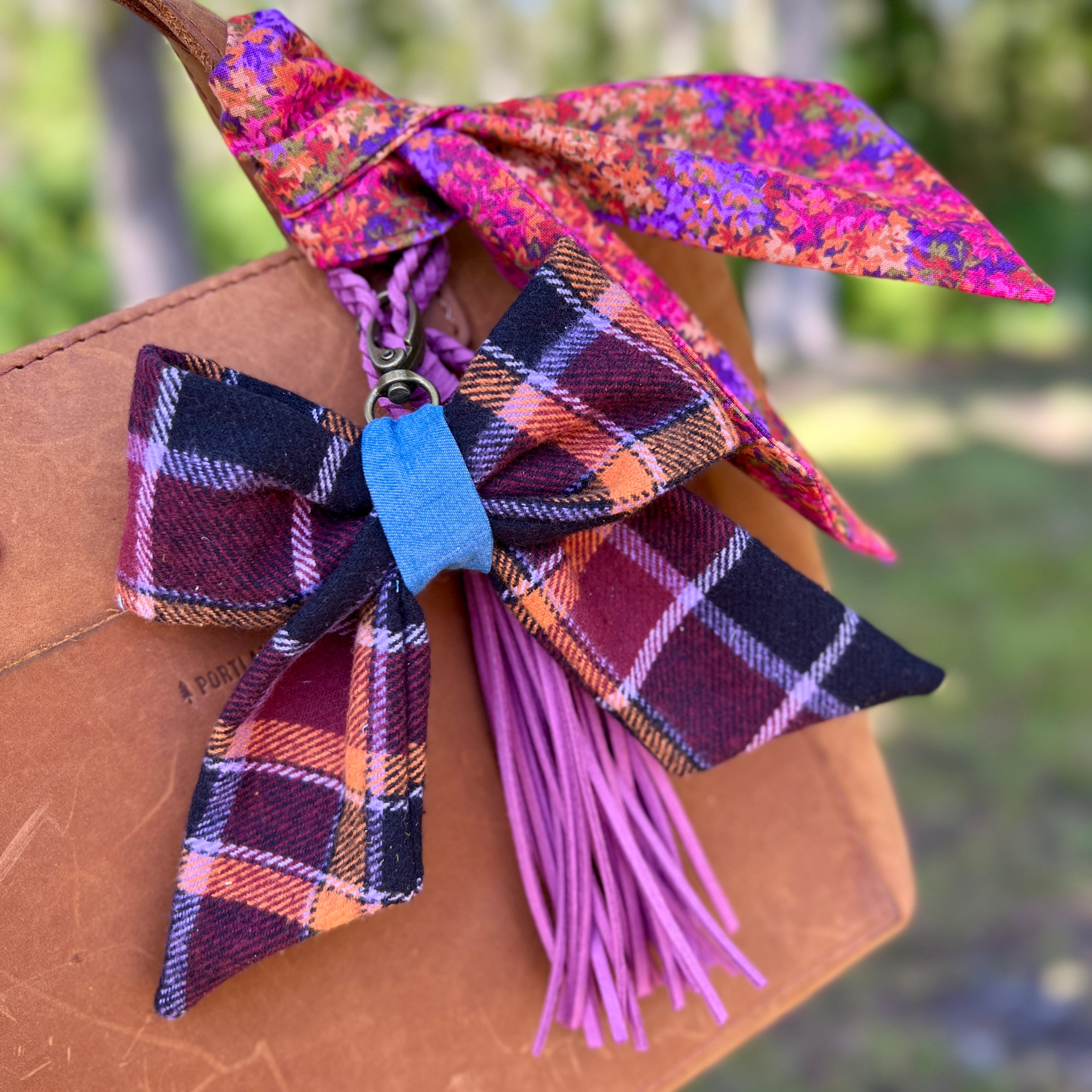 Colorful plaid bow with tassels on a brown leather surface