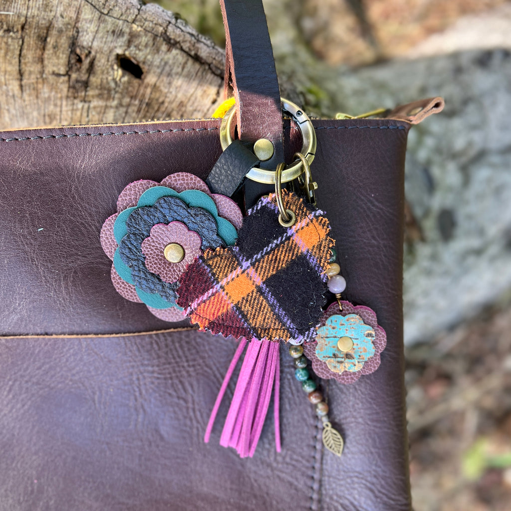 Colorful keychain with floral design attached to a leather bag against a natural background