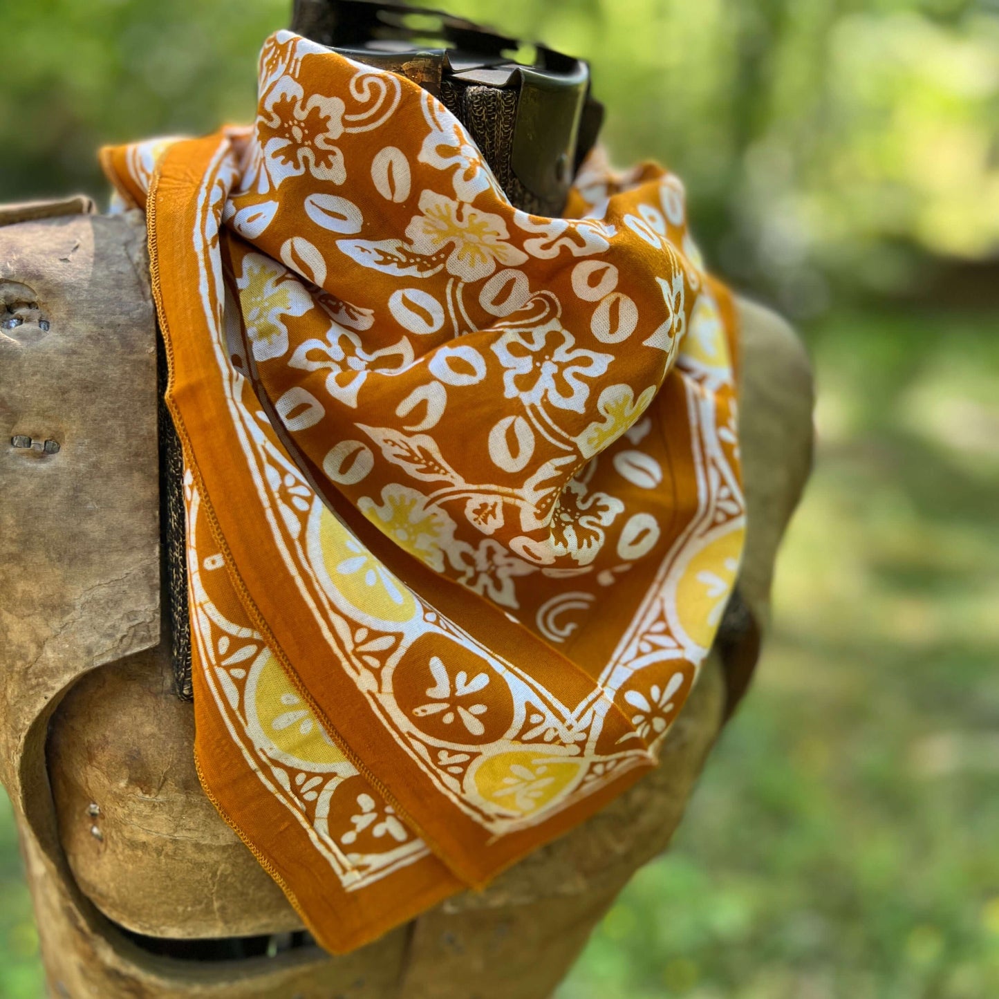 Orange bandana with white floral pattern draped over a rifle against a blurred green background