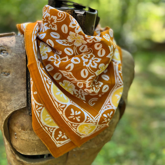 Orange bandana with white floral pattern draped over a rifle against a blurred green background