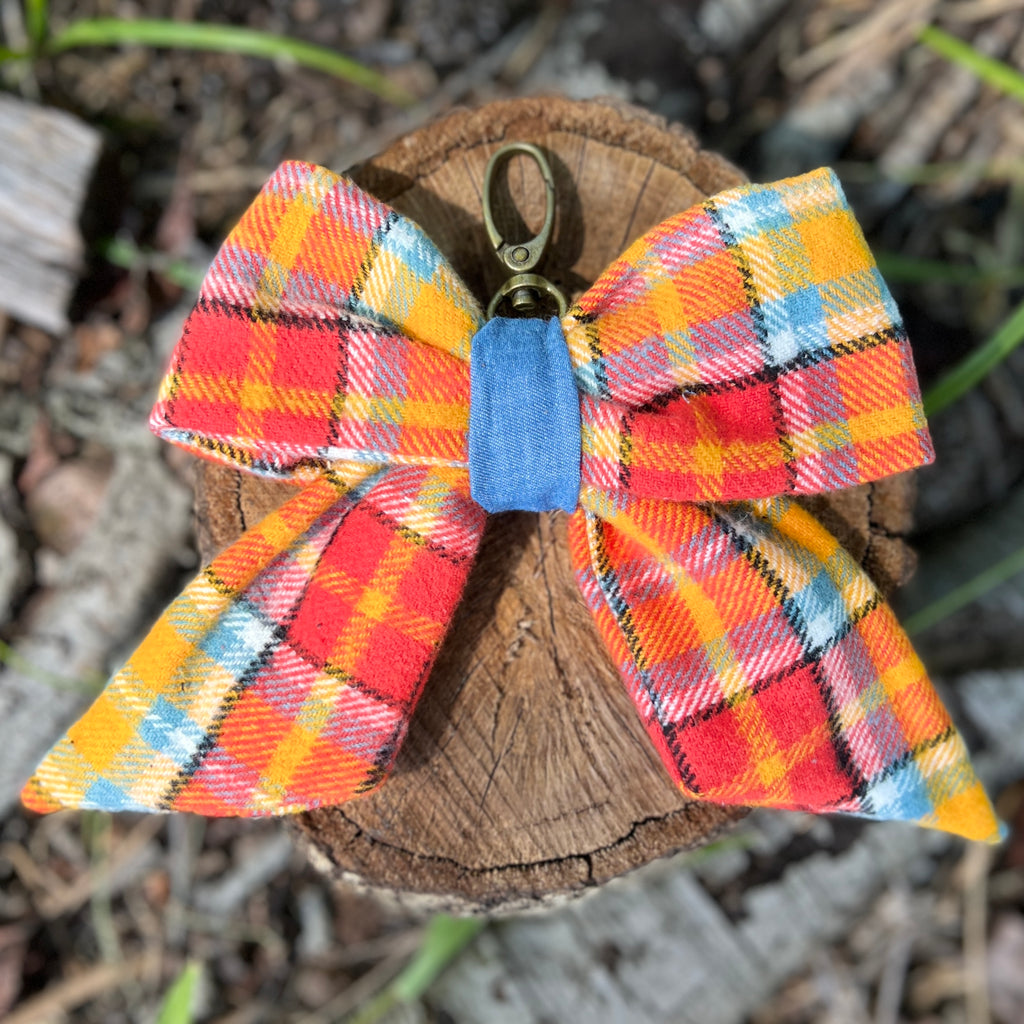 Plaid bow keychain with a blue tag on a wooden stump