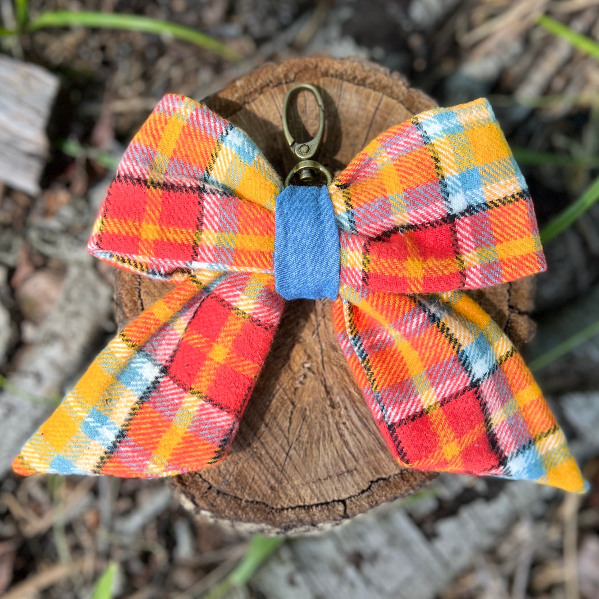 Plaid bow keychain with a blue tag on a wooden stump