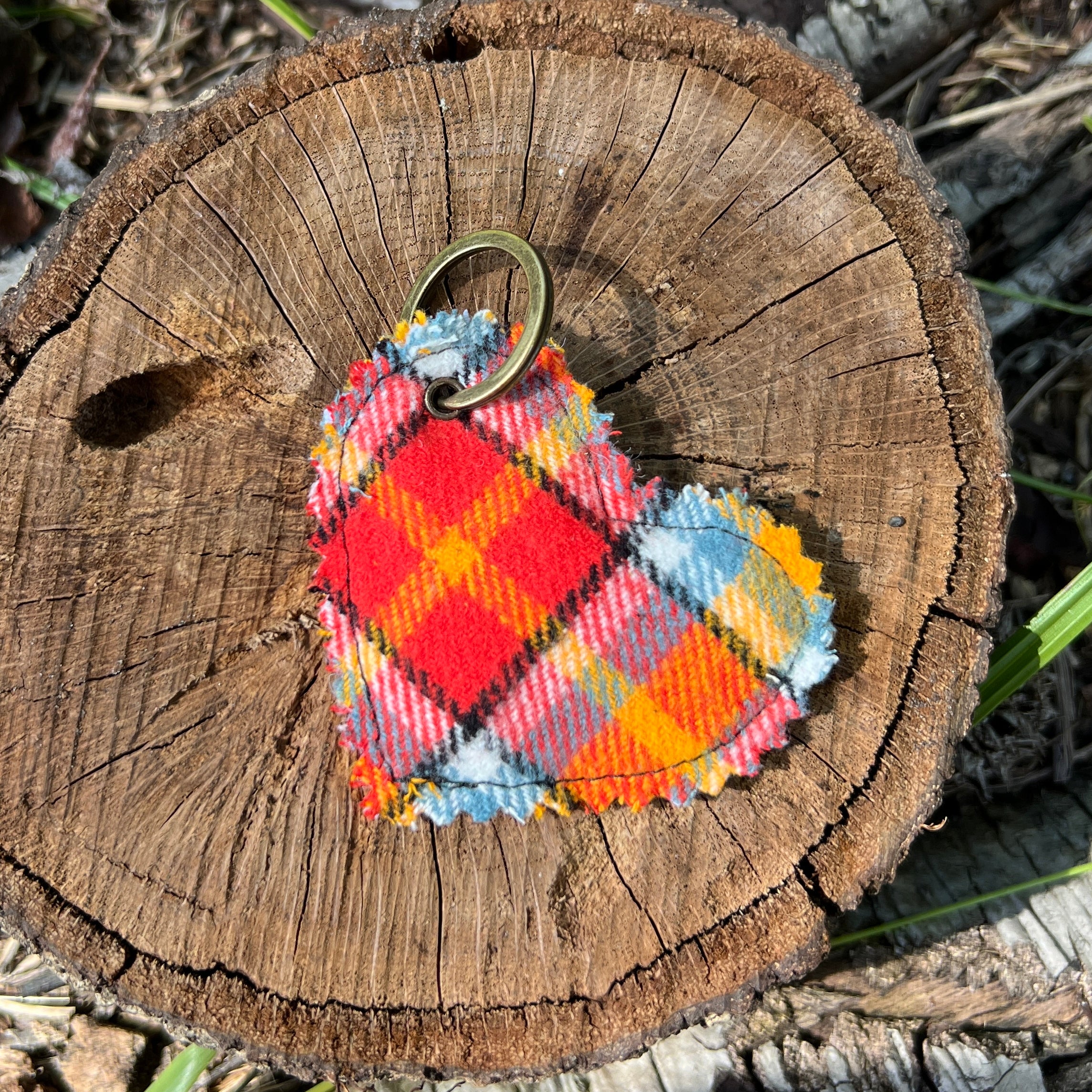 Colorful plaid keychain on a wooden log with natural background