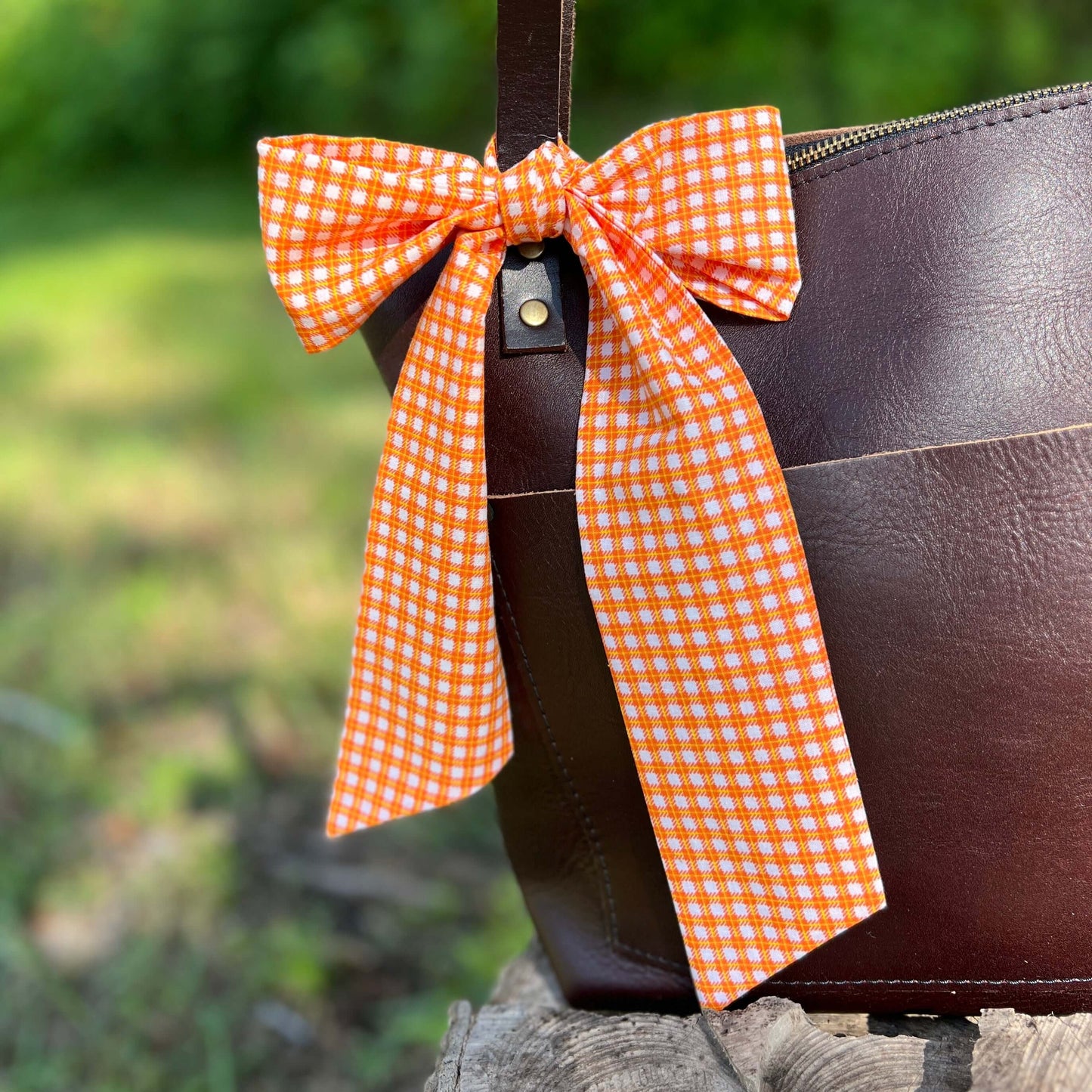 purse scarf in orange plaid tied in a bow on brown tote