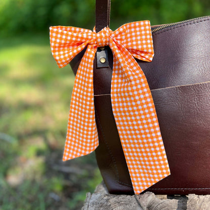 purse scarf in orange plaid tied in a bow on brown tote
