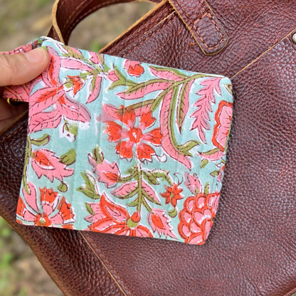 Floral patterned pouch held over a brown leather bag