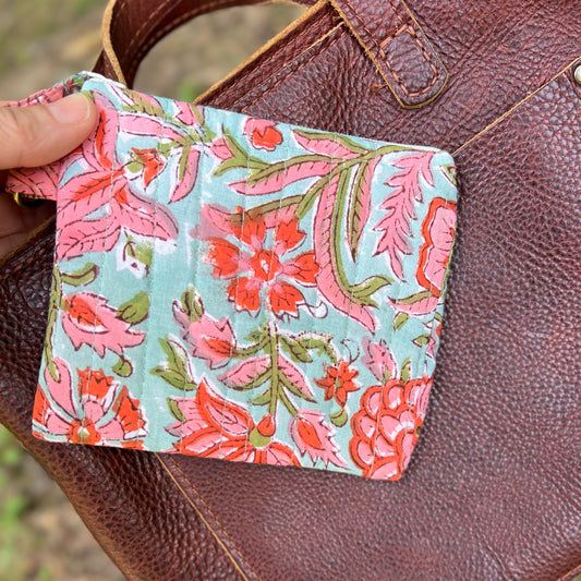 Floral patterned pouch held over a brown leather bag
