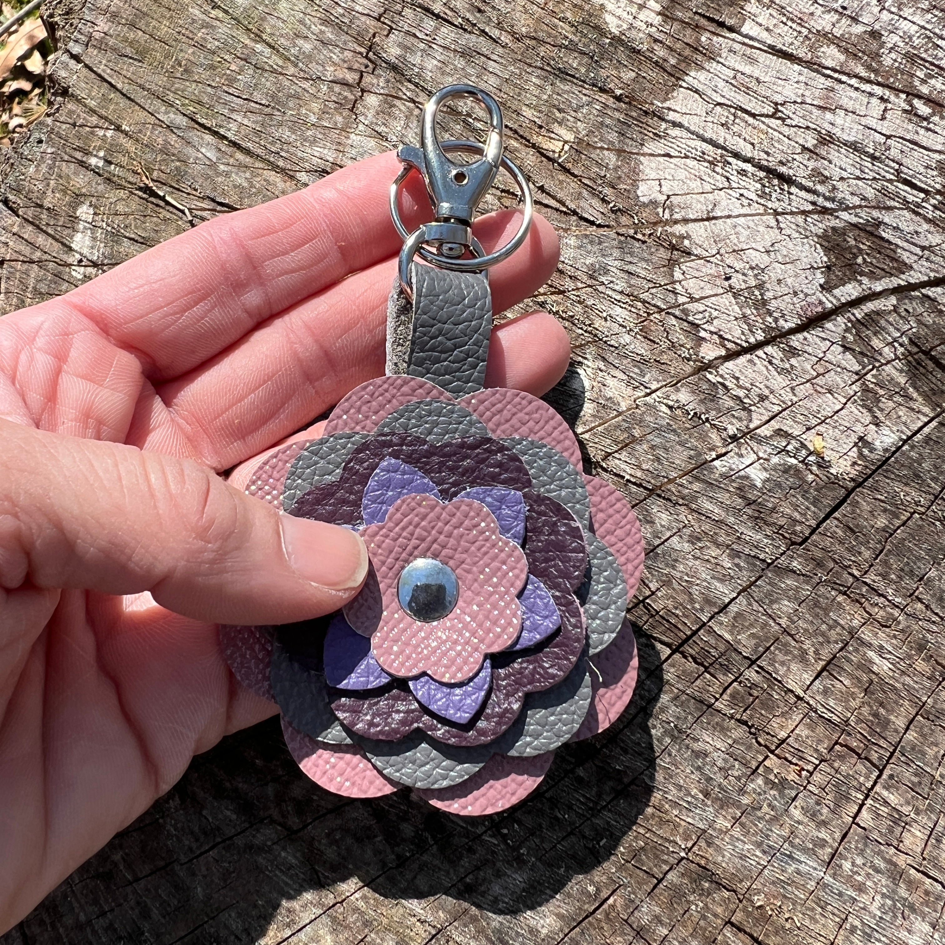 Floral-patterned keychain held by a hand on a wooden surface