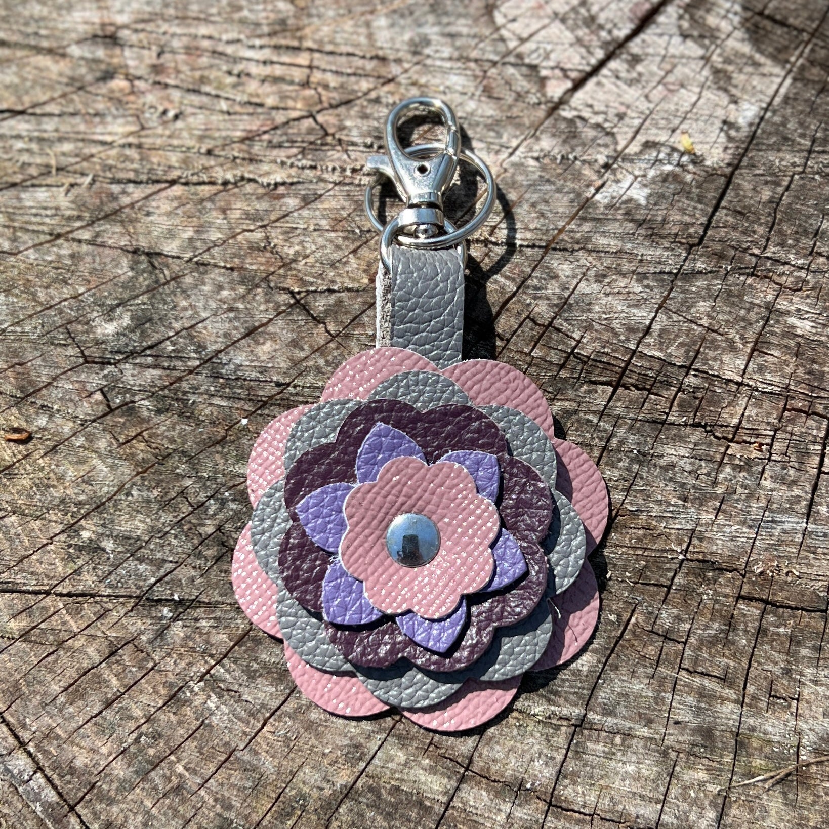 pink purple and grey leather flower key chain  on a wooden surface