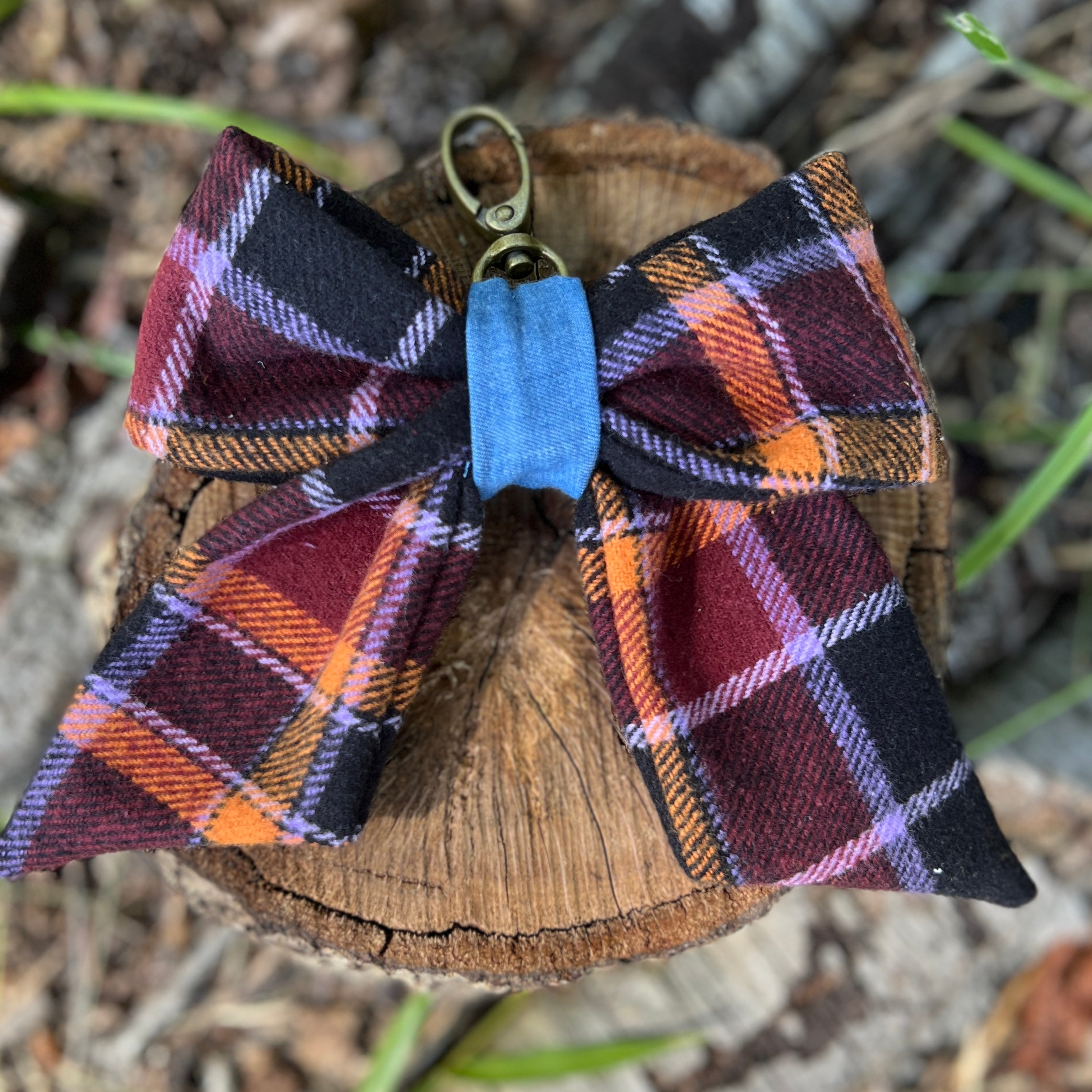 Plaid bow tie on a wooden block with grass in the background