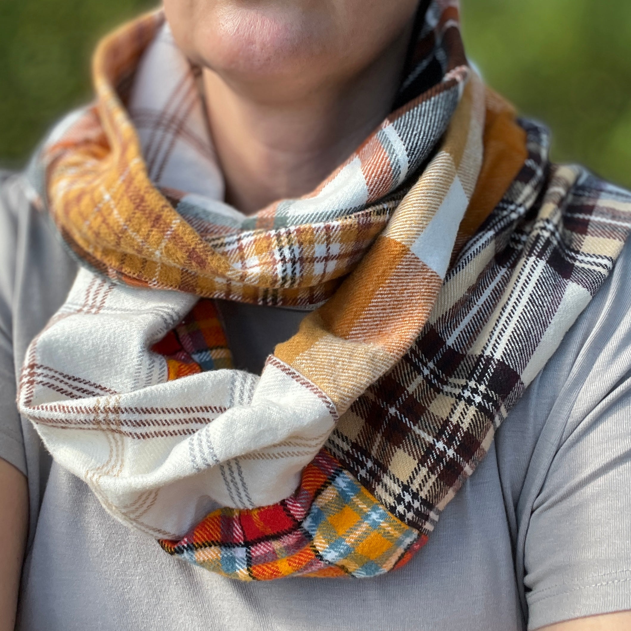 Person wearing a colorful plaid scarf with a blurred background