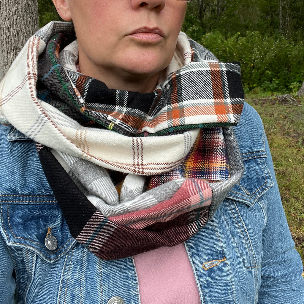 Person wearing a plaid scarf with a denim jacket outdoors