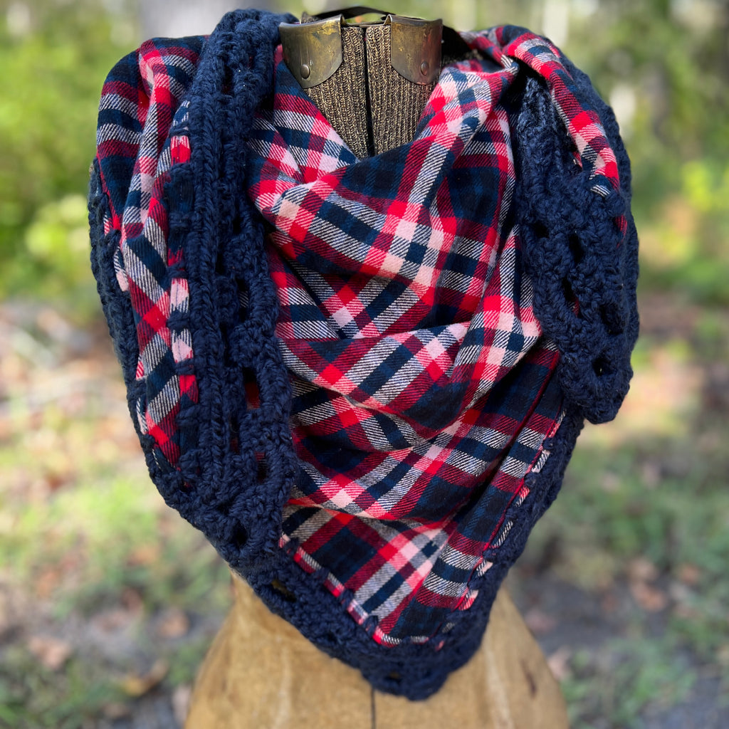 Plaid shawl with crochet border on a mannequin against a blurred natural background