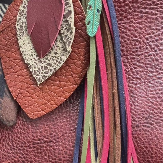 brown and deep red leather feather bag charm with tassel and flannel scarf on brown tote