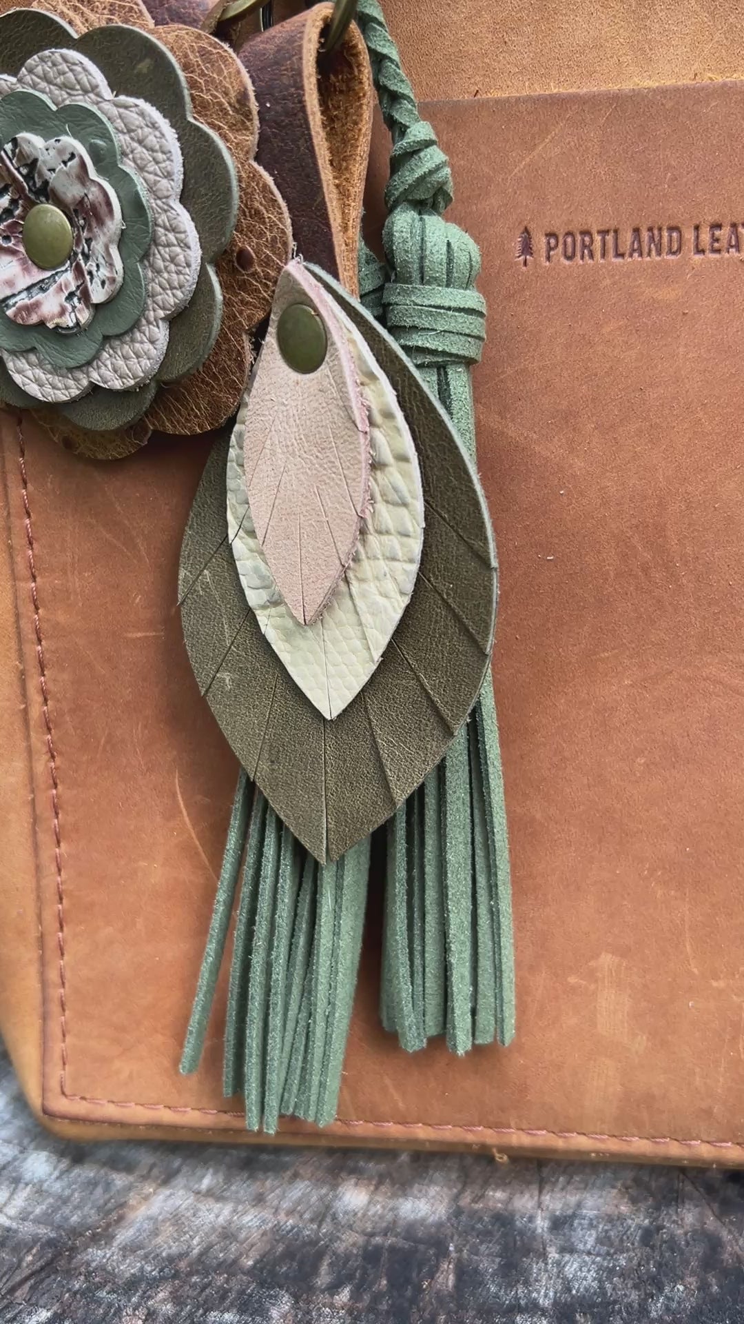 green and tan leather feather bag charm with green tassel and leather flower