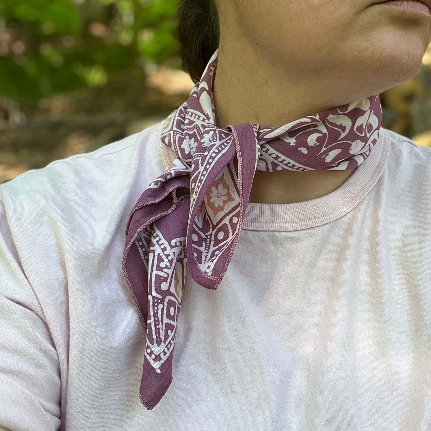 Person wearing a patterned purple scarf on a blurred natural background