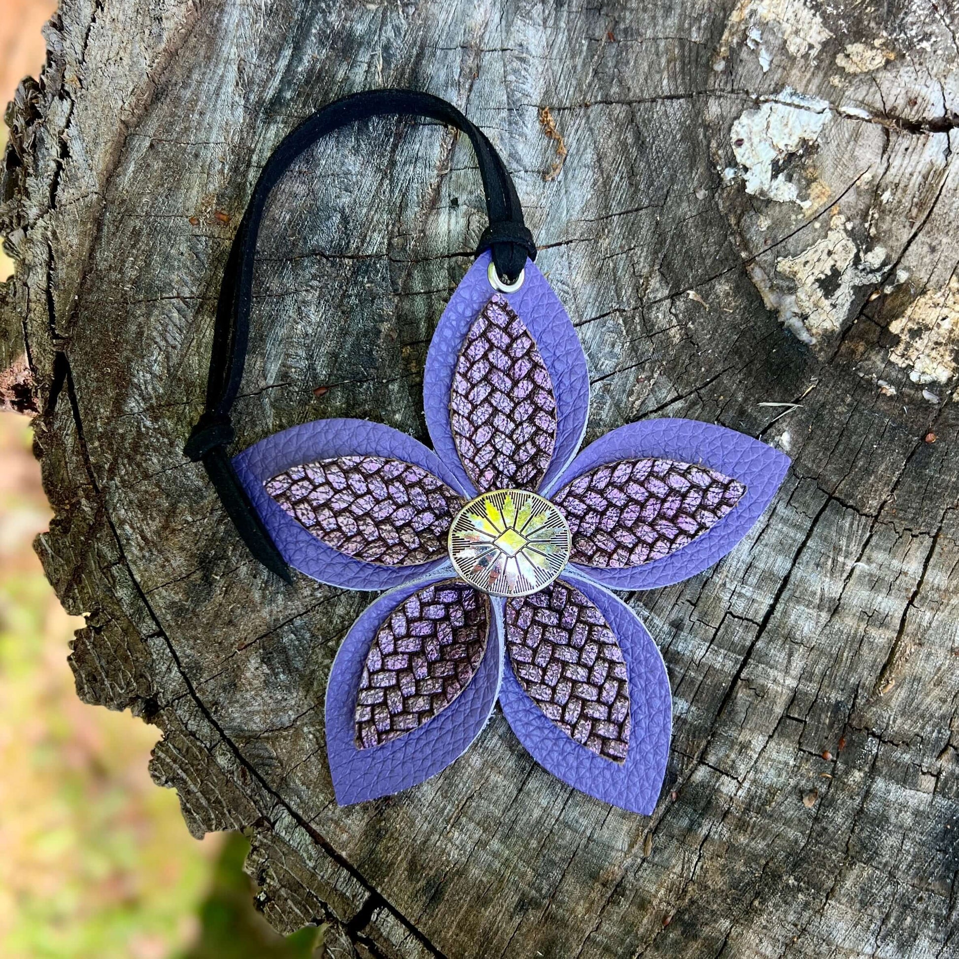 Purple leather flower bag charm with a textured center on a wooden surface