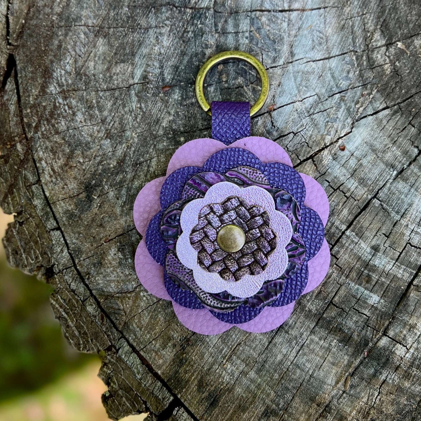 Purple leather flower bag charm on a wooden surface