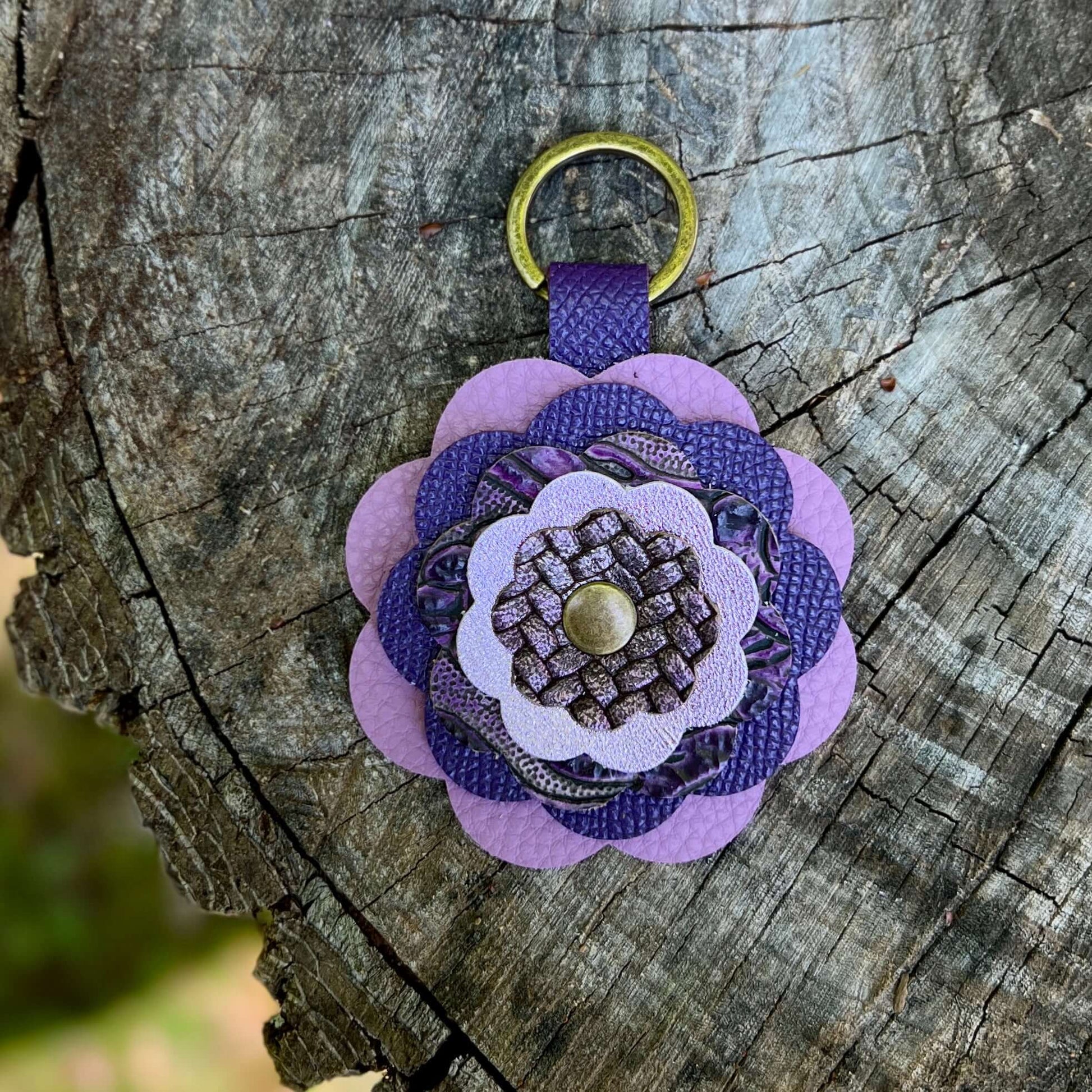 Purple leather flower bag charm on a wooden surface