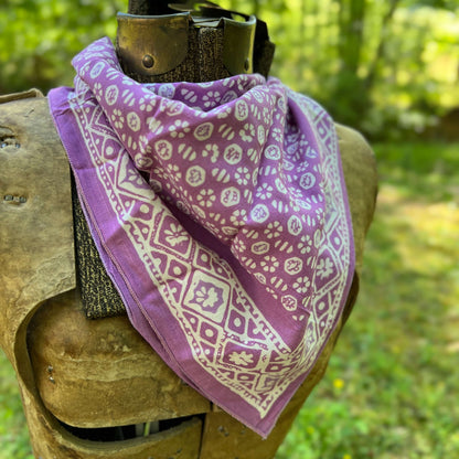 Purple bandana with white patterns draped over a wooden object outdoors.