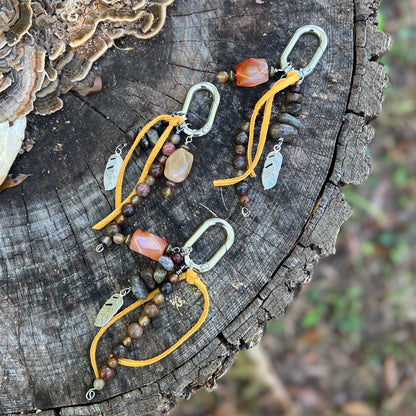 purse charm with yellow tassel and natural stone beads on wooden surface