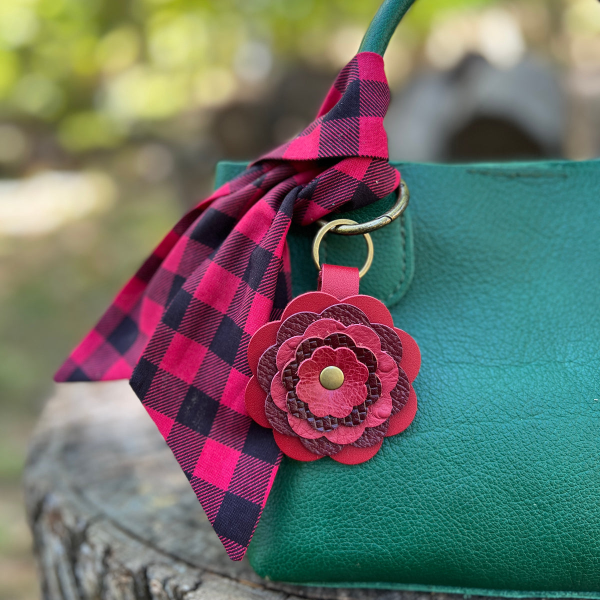 red and black plaid scarf with red leather flower charm on green handbag