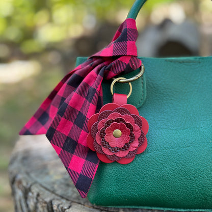 red and black plaid scarf with red leather flower charm on green handbag