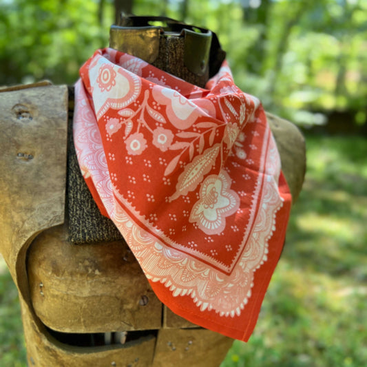 Red bandana with white patterns draped over a wooden object against a natural background