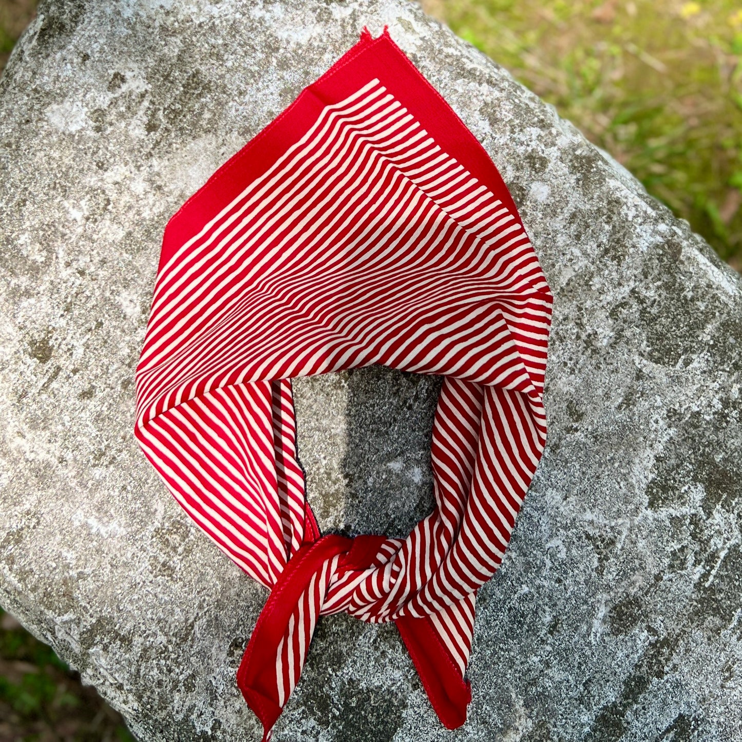 Red and white striped bandana tied on a stone surface