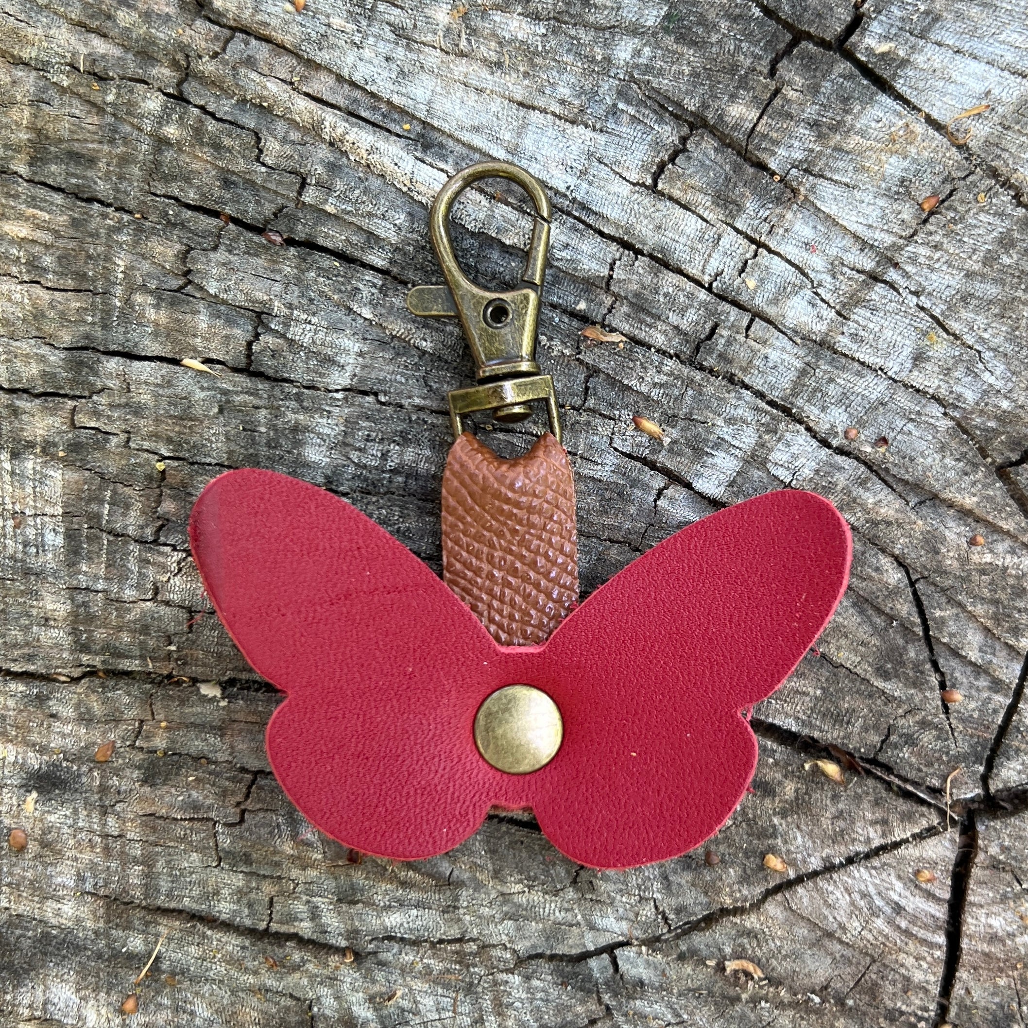 Butterfly-shaped keychain with a metal clasp on a wooden surface