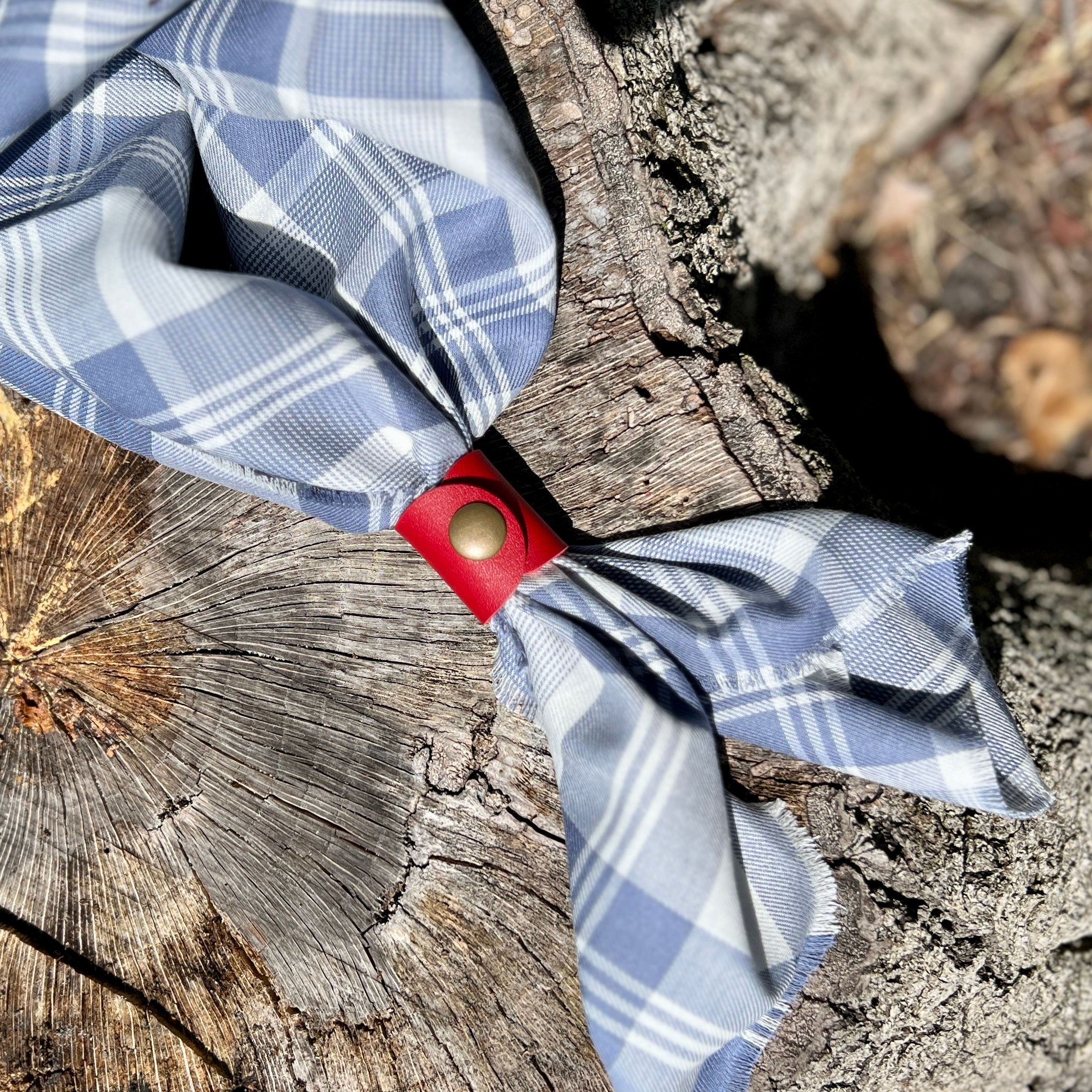Leather bandana slide snuggly holding a plaid scarf, featuring a quality metal snap for easy use.